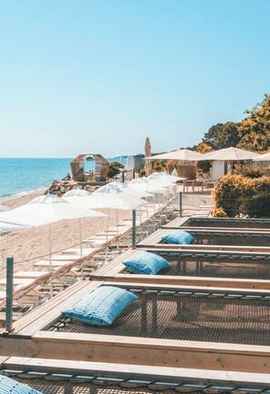 Un hotel frente al mar con mesas y sombrillas al aire libre.