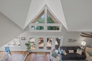 A spacious loft with a high ceiling, a large window, and a view of the outdoors.