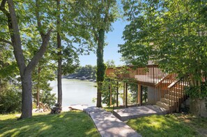 A lakeside property with a wooden deck, a stone pathway, and a view of the lake.