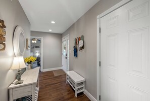 A hallway with a white bench, a lamp, and a door with a coat rack.