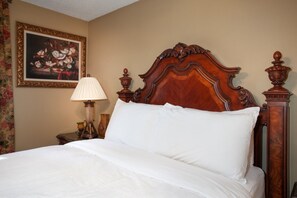 A neatly made bed with a wooden headboard, a bedside lamp, and a framed floral painting on the wall. - Moonridge Lodge | Fireplace, Grill & More! (Pigeon Forge)