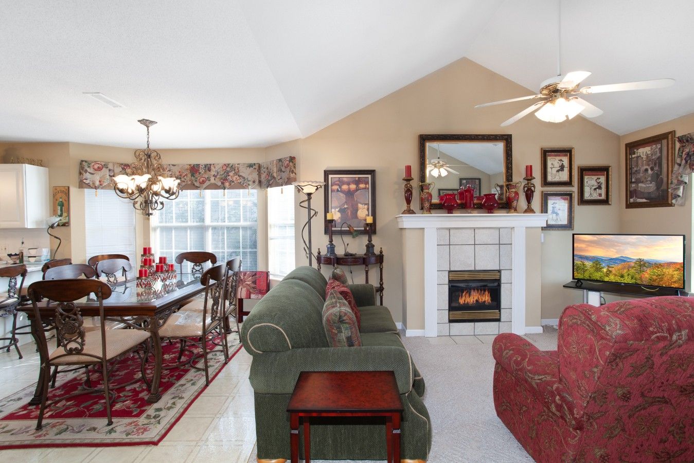 A living room with a fireplace, a television, and a dining area with chairs and a table.