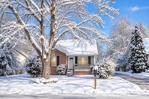 A residential house with a brick exterior, a front porch, and snow-covered trees. - Moonridge Lodge | Fireplace, Grill & More! (Pigeon Forge)