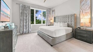 A bedroom with a bed, nightstands, a desk, a ceiling fan, and a window with curtains.