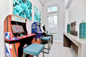Ein Raum mit zwei Spielautomaten, einer Sitzbank und einem Fenster.