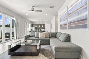 A modern living room with a sectional sofa, a glass coffee table, and a ceiling fan. - Beautiful Condo near Disney with Resort & Waterpark Access - B23-109 (Kissimmee)
