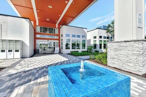 Ein modernes Gebäude mit Pool, überdachter Eingangspartei und einer Steinmauer.