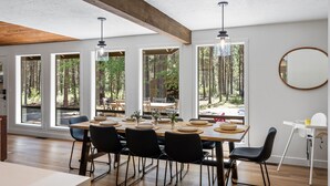 A dining area with a large table, chairs, and a view of the forest through large windows. - Cozy 3 bedroom house near Sunriver, 20 minutes to Mt.Bachelor.Hot tub Pool Table (Bend)