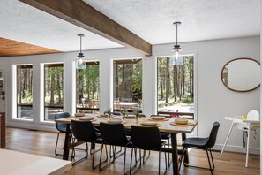 A dining area with a large table, chairs, and a view of the forest through large windows. - Cozy 3 bedroom house near Sunriver, 20 minutes to Mt.Bachelor.Hot tub Pool Table (Bend)