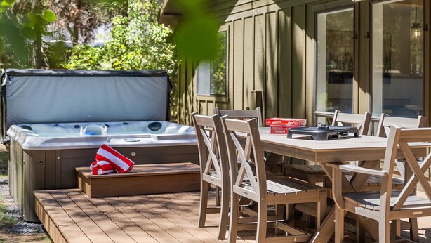 A hot tub with a cover, wooden deck, and outdoor furniture including a table and chairs. - Cozy 3 bedroom house near Sunriver, 20 minutes to Mt.Bachelor.Hot tub Pool Table (Bend)