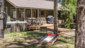 An outdoor seating area with a hot tub, a covered grill, and a shuffleboard table. - Cozy 3 bedroom house near Sunriver, 20 minutes to Mt.Bachelor.Hot tub Pool Table (Bend)