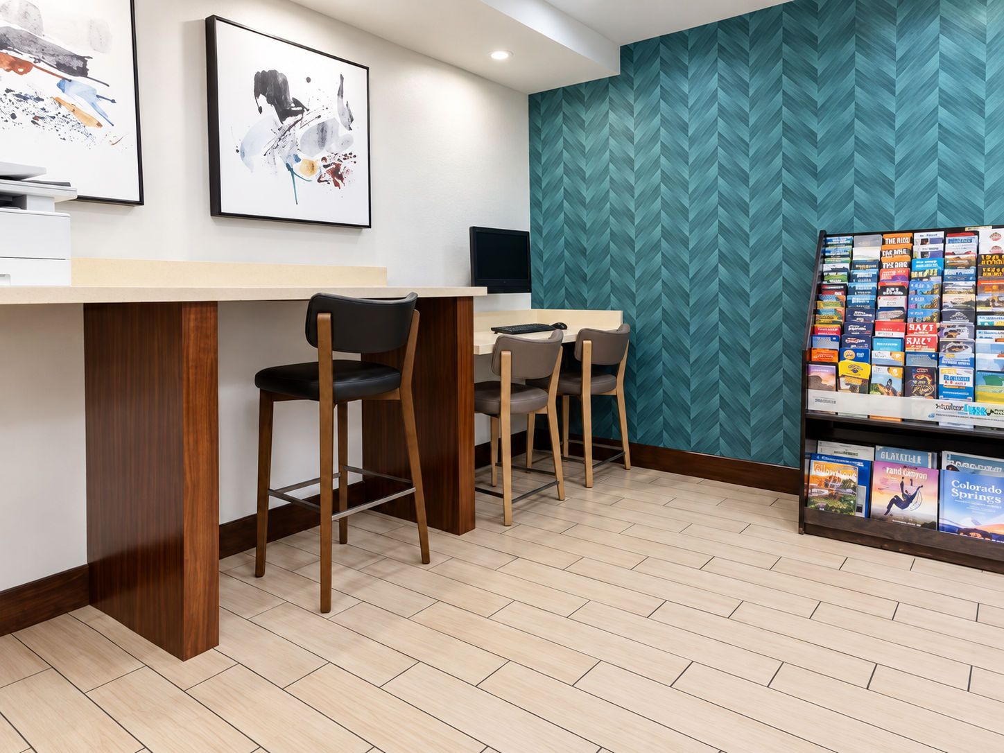 Eine moderne Bar mit zwei Barhocker, einem Flachbildfernseher und einem wandmontierten Bücherregal mit Reiseführern.