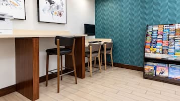 Eine moderne Bar mit zwei Barhocker, einem Flachbildfernseher und einem wandmontierten Bücherregal mit Reiseführern.