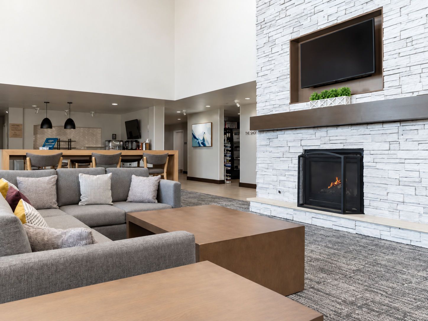 A modern living room with a fireplace, a dining area, and a kitchen in the background.