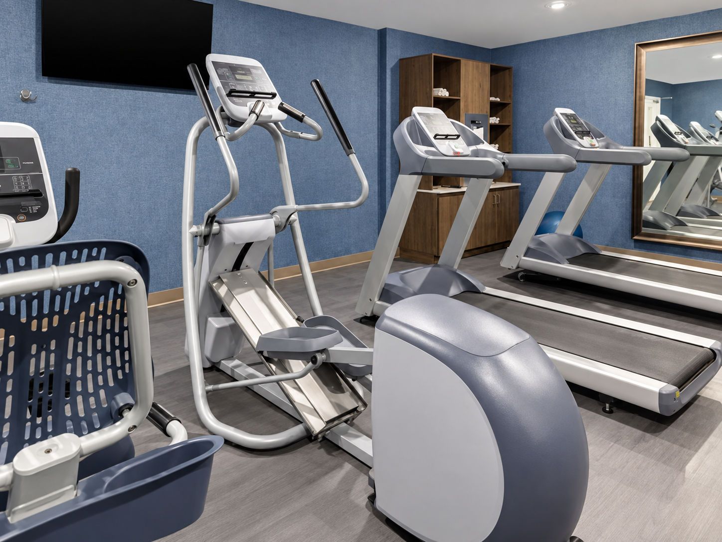Ein Fitnessstudio mit Laufbändern, Crosstrainern und Ergometer.