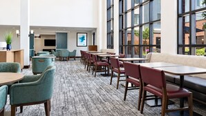 Et hotel lobby med siddeområder, et fladskærms-tv og store vinduer.