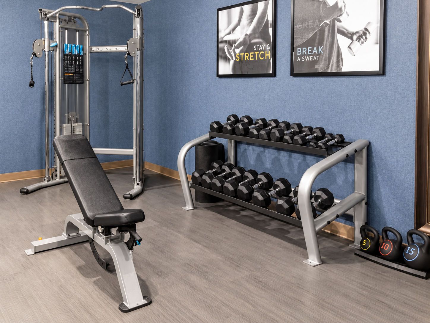A gym with a bench press, dumbbells, and a weight rack.