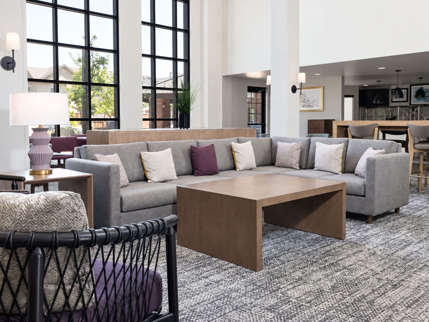 A modern living room with a sectional sofa, a coffee table, and a dining area in the background.
