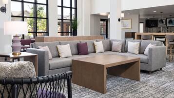 A modern living room with a sectional sofa, a coffee table, and a dining area in the background.