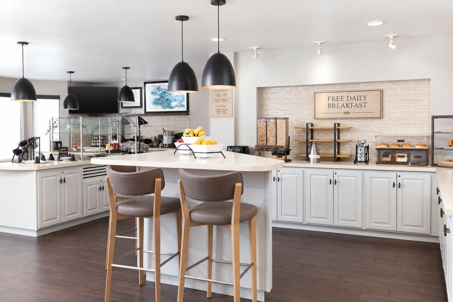 A modern kitchen with a central island, bar stools, pendant lighting, and a breakfast sign.