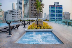 A rooftop pool with lounge chairs, a hot tub, and a cityscape view. - by Calamari.Homes - Infinitum 3302 - Bocagrande (Bocagrande)