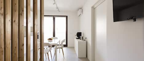 A modern kitchen with a dining area, a TV mounted on the wall, and a wooden partition.