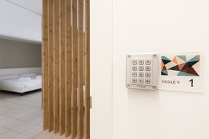 A room with a bed, a wooden partition, a keypad door lock, and a room number sign. - Visitsicilia Vasile 9 (Castellammare del Golfo)