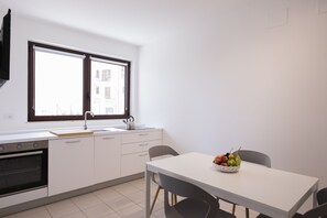 A modern kitchen with a white countertop, a kettle, and a fruit bowl on the table. - Visitsicilia Vasile 9 (Castellammare del Golfo)
