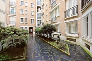 A courtyard with a stone pathway, surrounded by multi-story residential buildings with balconies. - Luxury at the foot of the Eiffel!! (Paris)