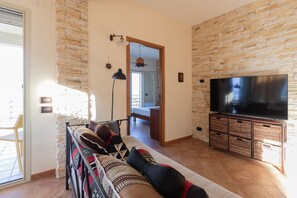 A living room with a sofa, television, and stone wall. - Visitsicilia Sabbia Dorata (ora n. 497) (Alcamo Marina)