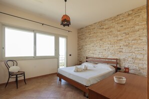 A bedroom with a bed, a chair, a table, and a stone wall. - Visitsicilia Sabbia Dorata (ora n. 497) (Alcamo Marina)