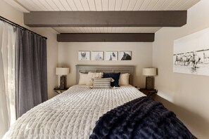 Ein Schlafzimmer mit einem Bett, zwei Nachttischlampen, einem Kopfteil und einer Wand mit drei gerahmten Bildern.