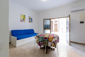 A room with a white sofa, a table with a colorful tablecloth, and two wall-mounted air conditioning units. - Visitsicilia Saramia 1 (Balestrate)