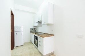 A compact kitchen with white cabinets, a wooden countertop, a built-in oven, and a refrigerator. - Visitsicilia Saramia 1 (Balestrate)
