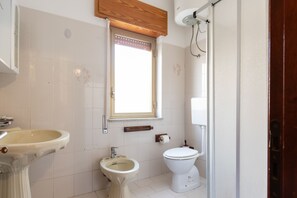 Ein Badezimmer mit Waschbecken, Bidet, Toilette und einem Fenster.