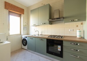 A compact kitchen with a washing machine, a sink, a stove, and cabinets. - Visitsicilia Saramia 2 (Balestrate)