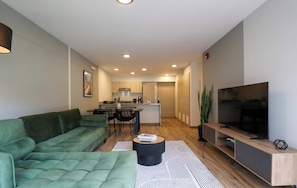 A modern living room with a green sofa, a coffee table, and a TV on a wooden stand. - w* | Bright 3BR with Terrace in Miraflores (Miraflores)