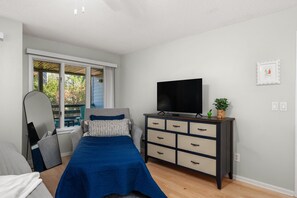 A bedroom with a bed, a dresser, a television, and a window with a view of trees. - Duck Soundside Retreat King Beds, Pool, Sound Views & Great Amenities! (Kitty Hawk)