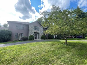 A two-story house with a stone facade, a front lawn, and a tree. - Peaceful 2-bedroom house near Guthrie Clinic and 40 min to 2 Finger Lakes (Sayre)