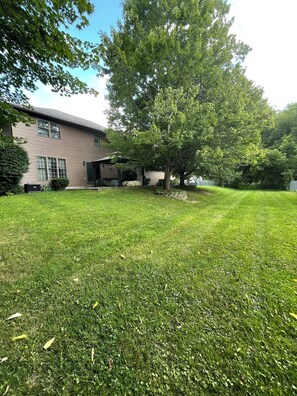 A residential property with a well-maintained lawn, a large tree, and a two-story house with a garage. - Peaceful 2-bedroom house near Guthrie Clinic and 40 min to 2 Finger Lakes (Sayre)