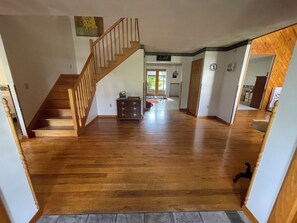 Ein geräumiges Zimmer mit Holzboden, einer Holztreppe und Blick auf einen Essbereich.