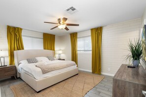A bedroom with a bed, a ceiling fan, a nightstand, a lamp, and a potted plant. - Desert Diamond - Scottsdale 4 BR, Pool, Fire Pit, Ping Pong and games (Scottsdale)