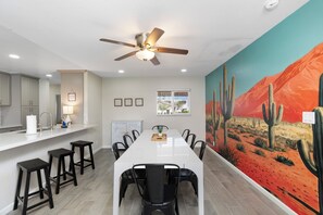 A modern kitchen with a white countertop, bar stools, and a ceiling fan. - Desert Diamond - Scottsdale 4 BR, Pool, Fire Pit, Ping Pong and games (Scottsdale)