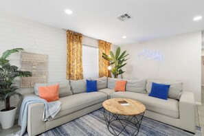 A modern living room with a sectional sofa, a coffee table, and a potted plant. - Desert Diamond - Scottsdale 4 BR, Pool, Fire Pit, Ping Pong and games (Scottsdale)