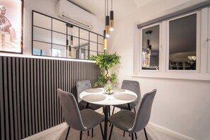 A dining area with a round table, four chairs, a potted plant, and a modern pendant light fixture. - 3 bed Luxury Home With hot Tub, Free Parking and EV (Northwood)