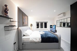 A modern bedroom with a bed, a television, and a window. - 3 bed Luxury Home With hot Tub, Free Parking and EV (Northwood)