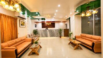 A hotel lobby with leather sofas, a reception desk, and a marble wall.