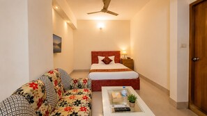Una habitación de hotel con una cama, un sofá, una mesita de café y un ventilador de techo.