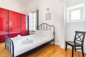 A bedroom with a bed, a chair, a red wardrobe, and a window. - w* | Enchanting Apartment in the Heart of Florence (Firenze)