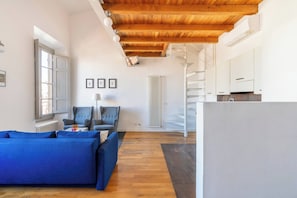 A modern living room with a blue sofa, a grey armchair, and a wooden ceiling. - w* | Enchanting Apartment in the Heart of Florence (Firenze)